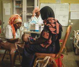 MSF aid worker treats child on mother's lap in Ethiopia during nutritional crisis in Afar region