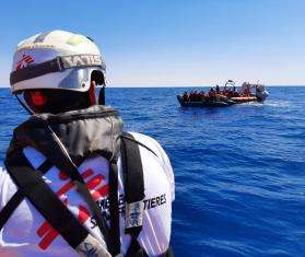 An MSF search and rescue staff member approaches a boat in distress in the Mediterranean.