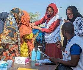 A group of MSF medics are clustered together outside in Dadu district, Pakistan, caring for women and their children.