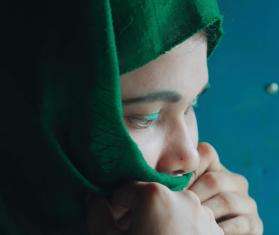 Profile of a young Rohingya woman in a green headscarf in Bangladesh.