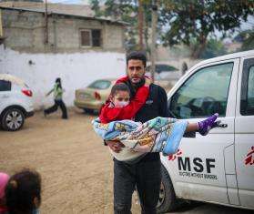 A Palestinian man carries an injured child to MSF's clinic at Rafah Indonesian Hospital in Gaza.