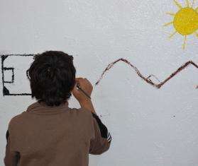A child draws a sun and mountains on the wall during an art therapy session in Al-Hol camp, northeast Syria.
