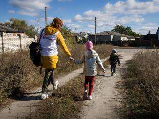 MSF psychologist and children walk outside in Ukraine.