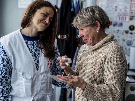 MSF psychologist stands beside an elderly woman wiping tears away in Ukraine.