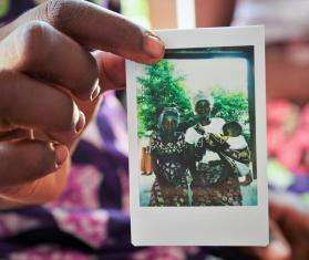 A woman holds a polaroid photo of a family in Mozambique.