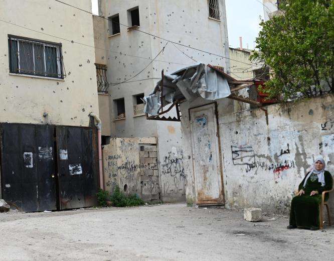 A Palestinian woman sitting beside a wall in the West Bank.