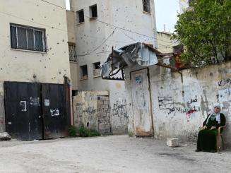 A Palestinian woman sitting beside a wall in the West Bank.