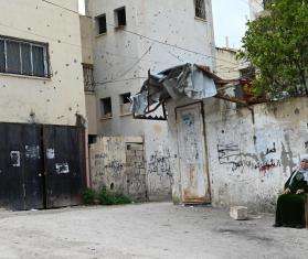 A Palestinian woman sitting beside a wall in the West Bank.