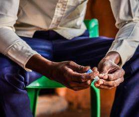 A diabetic refugee from Somalia sits in Dagahaley camp, Kenya, holding his insulin.