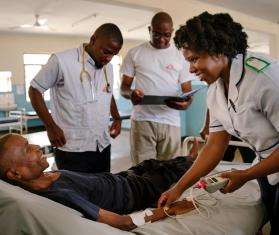 A group of MSF medics gathered around a patient in a hospital bed.
